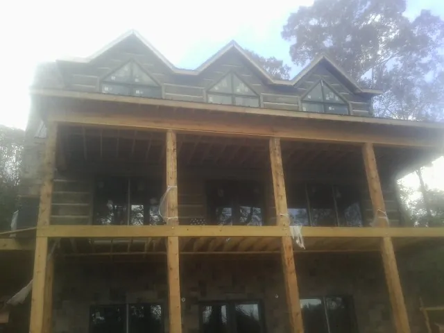 Dormers and porch framing on a large log home under construction — Roof Coating work by our crew in Yaphank