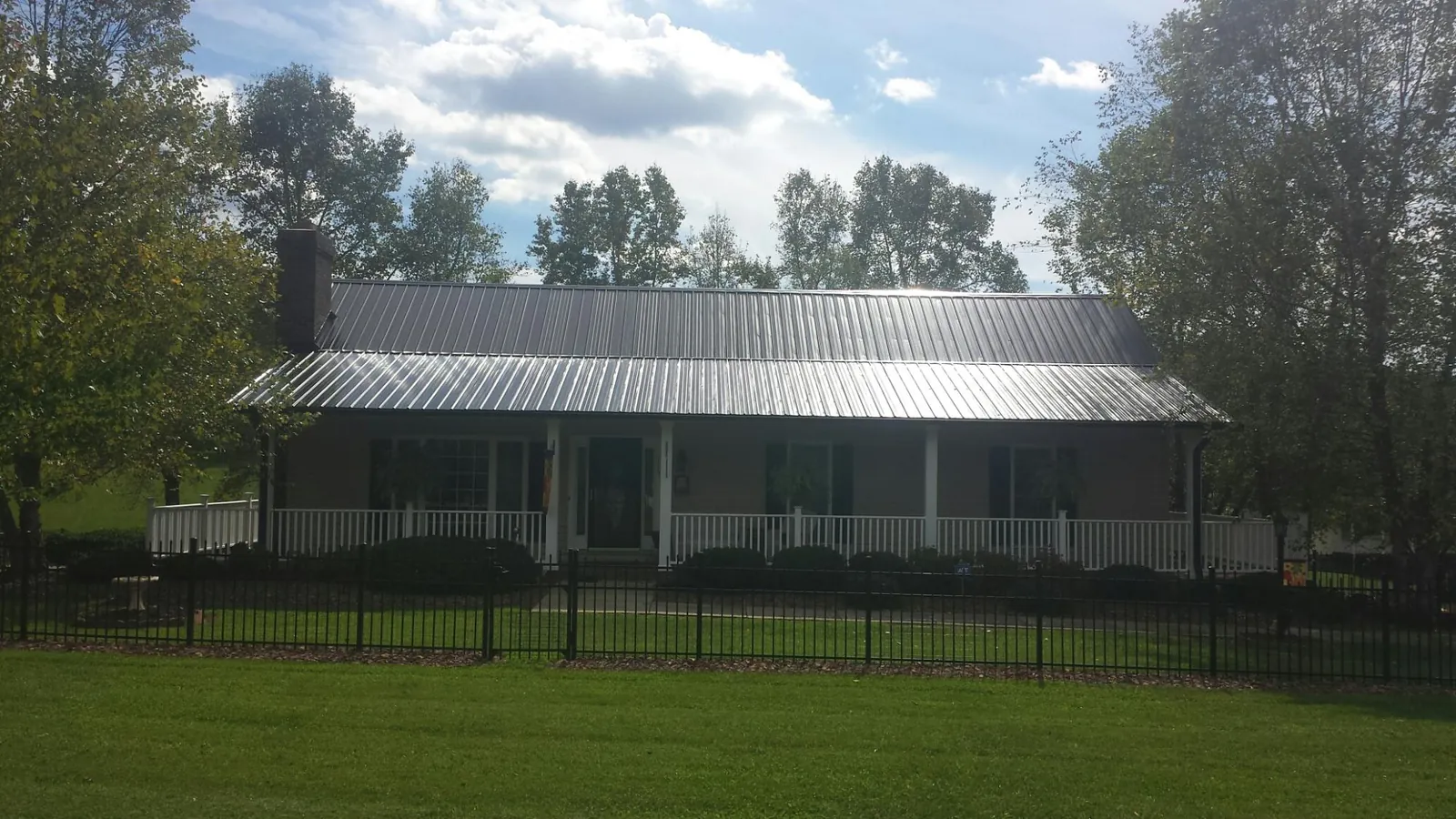 Gray metal roof on a brick ranch with a full width front porch — Gutter Guard Installation work by our crew in Yaphank