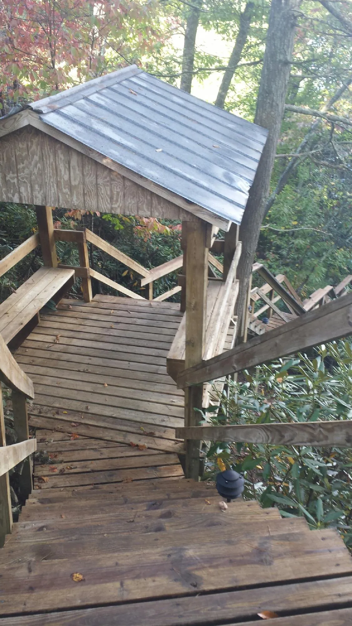 Metal roofed shelter over wooden steps on a wooded walkway — Skylight Repair & Installation work by our crew in Yaphank