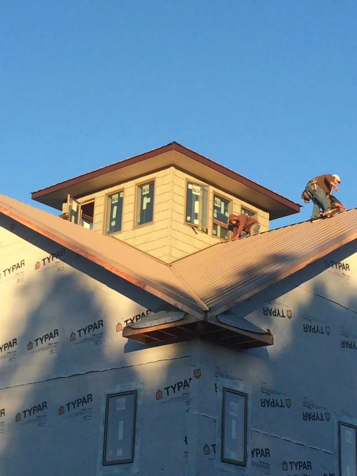 Roofers working around a rooftop cupola on a new metal roof at sunset — Roof Waterproofing in Yaphank by Roofing Brothers